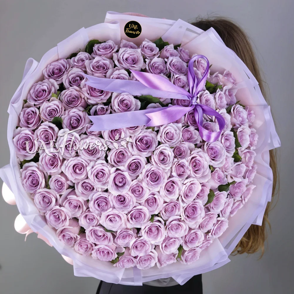 A bouquet of 100 purple roses	in purple wrapping paper tied with a purple ribbon