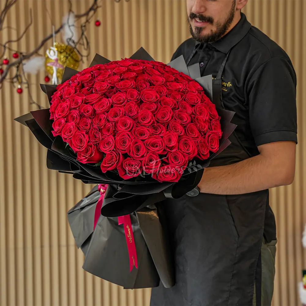 A romantic bouquet of 100 red roses in black wrapping paper tied with black ribbon