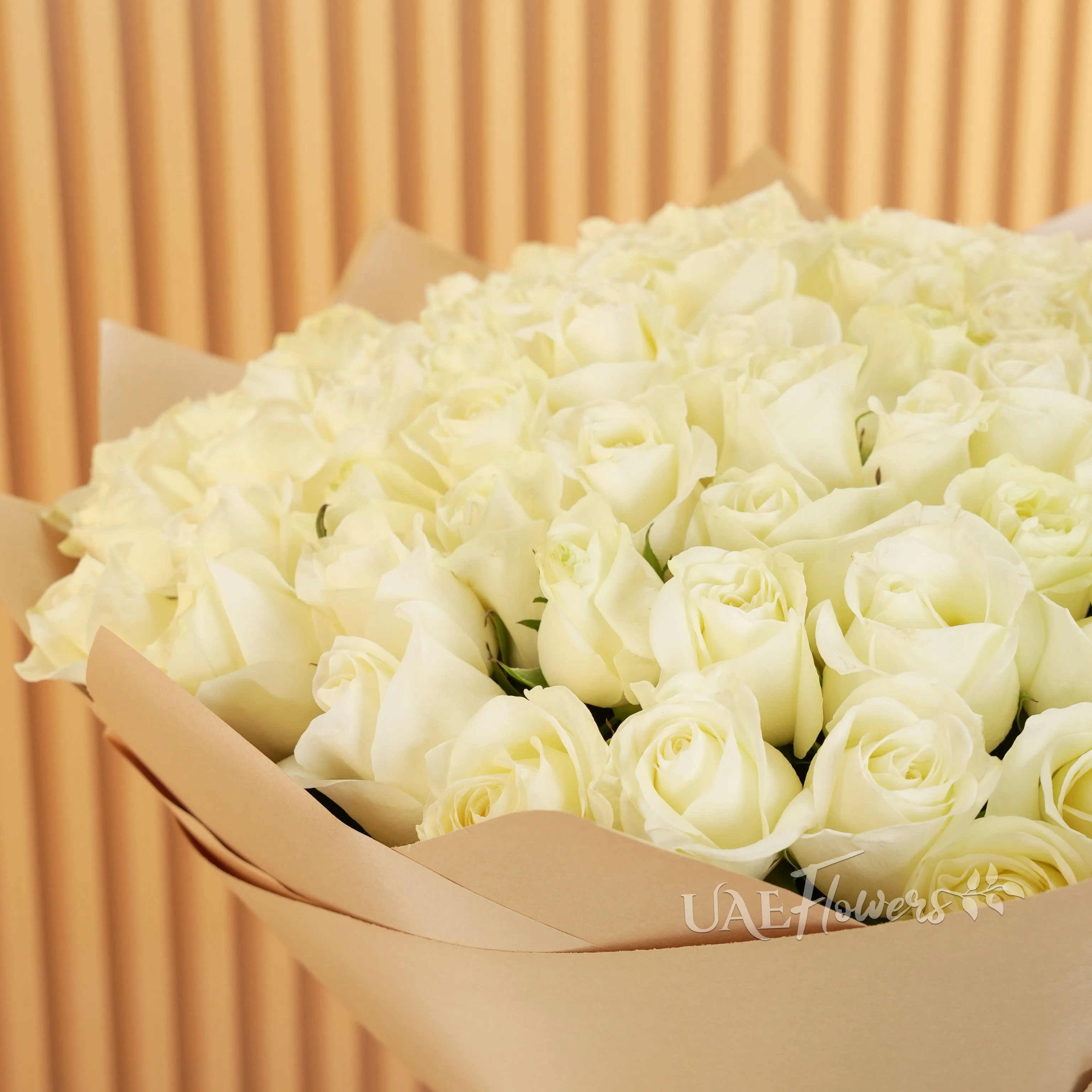 A bouquet of 100 white roses in brown wrapping paper tied with brown ribbons