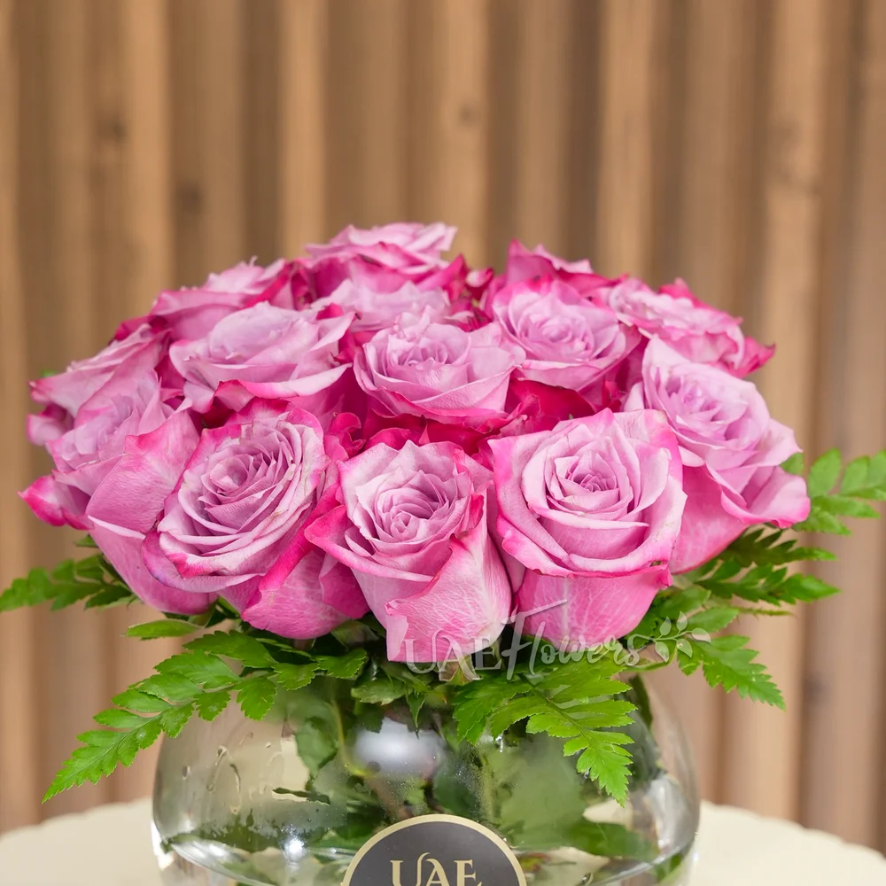 Clear glass vase with 15 purple roses and green fillers