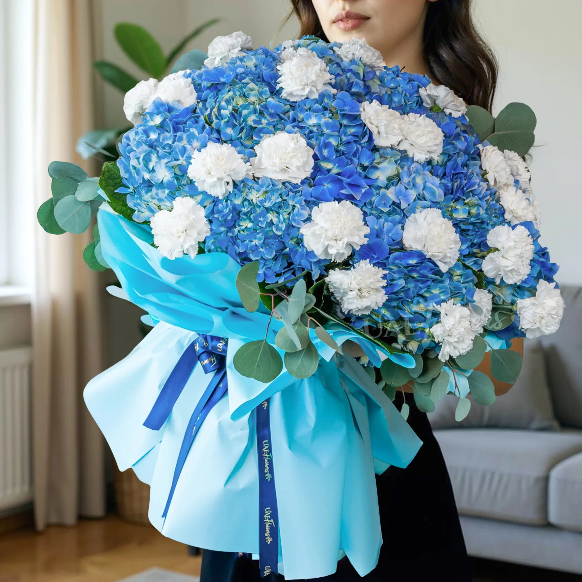 15 blue hydrangeas, 20 white carnations, and fillers, wrapped in paper with ribbon